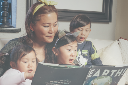 Asian mom reading a book to her three children