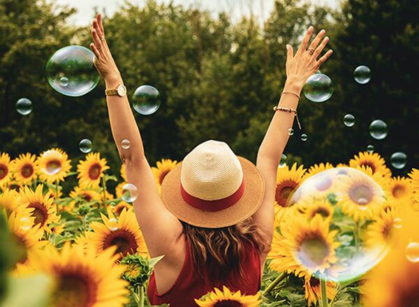 woman raising hands in a sunflower field