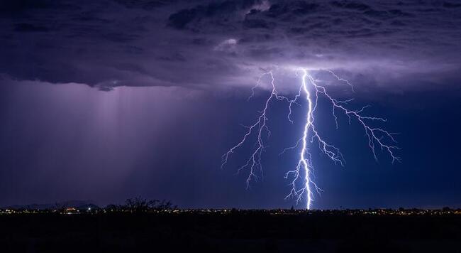 A bright lightning bolt striking down at a city
